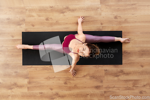 Image of woman doing yoga exercise on mat at studio