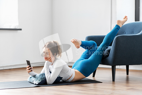 Image of woman with smartphone stretching yoga at home