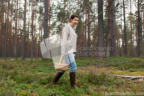 Image of woman with basket picking mushrooms in forest