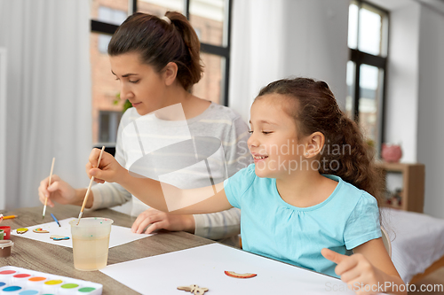 Image of happy mother with little daughter drawing at home