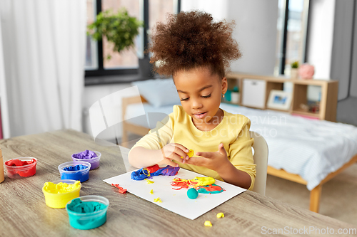 Image of little girl with modeling clay playing at home