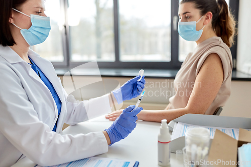 Image of female doctor with syringe vaccinating patient