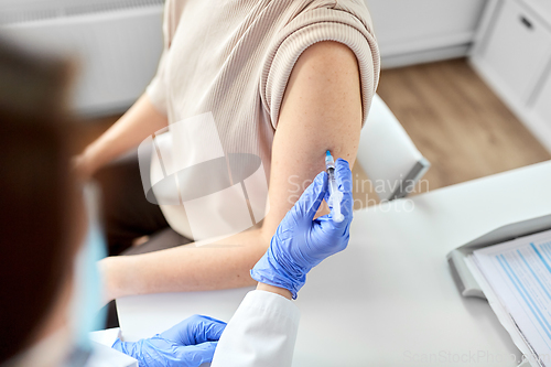 Image of female doctor with syringe vaccinating patient