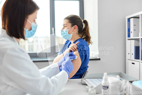 Image of doctor with syringe vaccinating medical worker