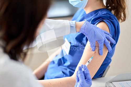 Image of doctor with syringe vaccinating medical worker