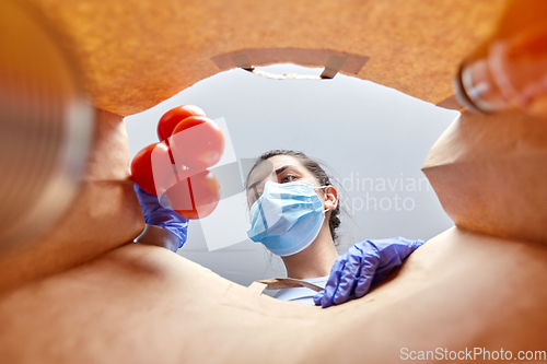 Image of woman in gloves and mask with food in paper bag