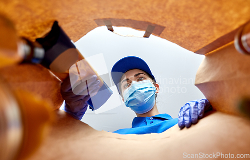 Image of delivery girl in gloves and mask with food in bag