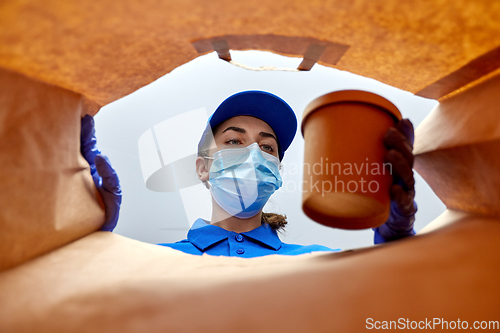 Image of delivery girl in gloves and mask with food in bag