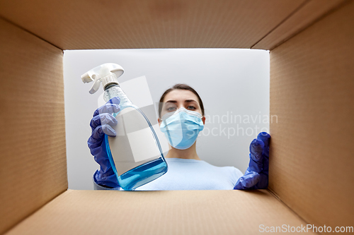 Image of woman in mask taking cleaning supplies from box
