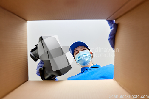 Image of woman in mask packing vr glasses to parcel box