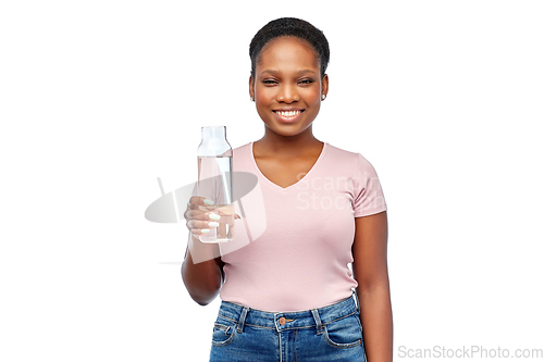 Image of happy african woman drinks water from glass bottle