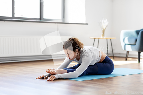 Image of young woman doing yoga exercise at home