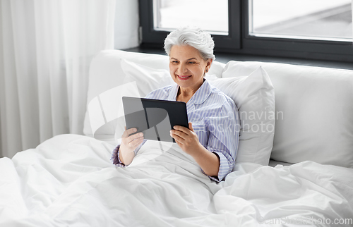 Image of senior woman with tablet pc in bed at home bedroom