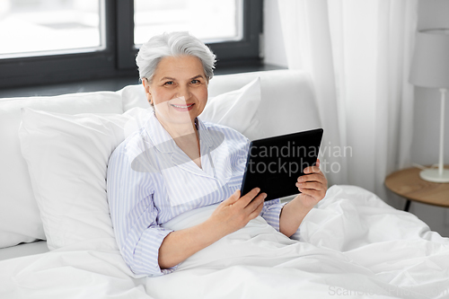 Image of senior woman with tablet pc in bed at home bedroom