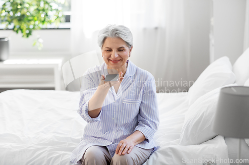 Image of happy senior woman recording voice on smartphone