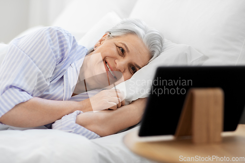 Image of happy senior woman with tablet pc in bed at home