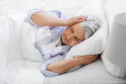 Image of annoyed senior woman with headache in bed at home