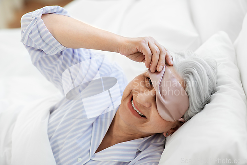 Image of senior woman with eye sleeping mask in bed at home