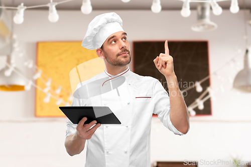 Image of male chef with tablet computer pointing finger up