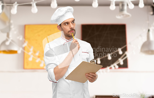 Image of thinking male chef with clipboard at restaurant