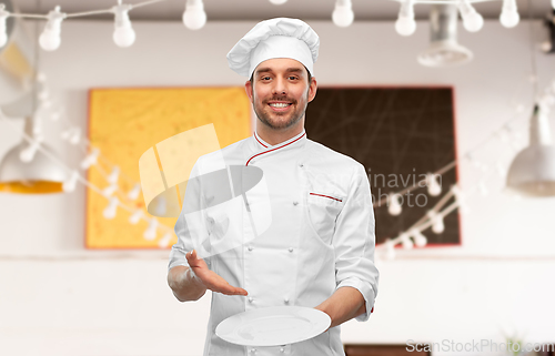 Image of happy smiling male chef holding empty plate