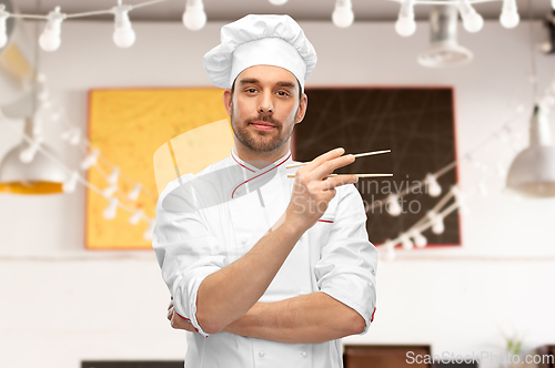 Image of serious male chef with chopsticks