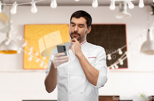 Image of thinking male chef with smartphone