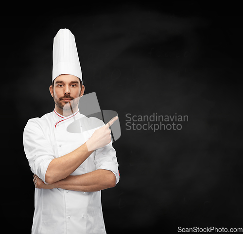 Image of male chef in toque pointing finger on black