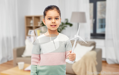 Image of smiling girl with toy wind turbine at home