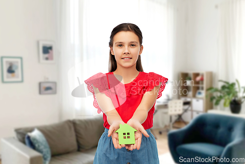 Image of smiling girl holding green house icon at home