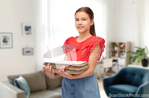 Image of smiling girl sorting paper waste at home