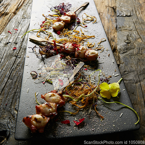 Image of Snack from pieces of an octopus on a wooden skewer. Film effect