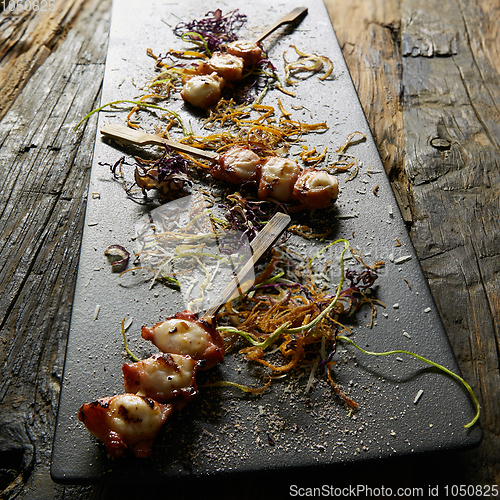 Image of Snack from pieces of an octopus on a wooden skewer. Film effect