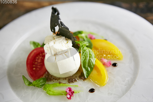 Image of Burrata - Italian cheese, which is an excellent combination of mozzarella and cream. Its name comes from the word burro, which means butter. Each ball is a bag of mozzarella stuffed with stuffing.