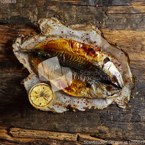 Image of Fish with lime on parchment paper on a black wooden background. Top view.