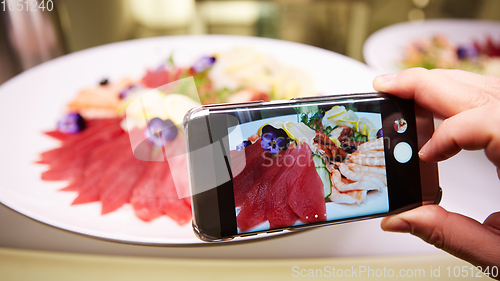 Image of Hands taking picture of sashimi japan food with smartphone.