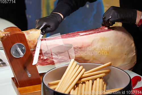Image of Sliced dried chamon prosciutto. A man cuts a jamon, a warm toned
