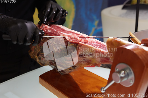 Image of Sliced dried chamon prosciutto. A man cuts a jamon, a warm toned