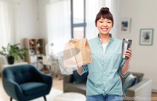 Image of woman with paper bag and tumbler for hot drinks