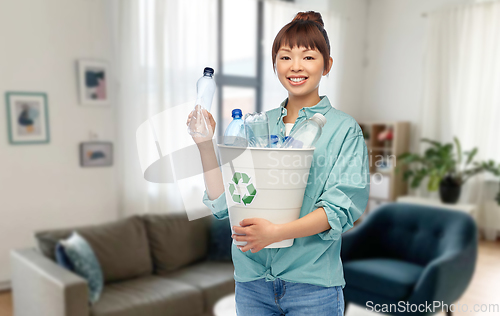 Image of smiling young asian woman sorting plastic waste