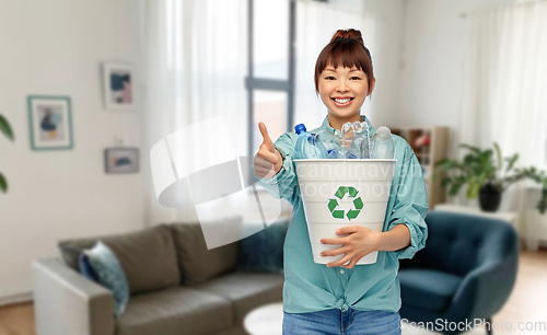 Image of smiling young asian woman sorting plastic waste