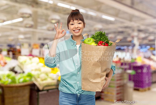 Image of happy asian woman with food in paper shopping bag