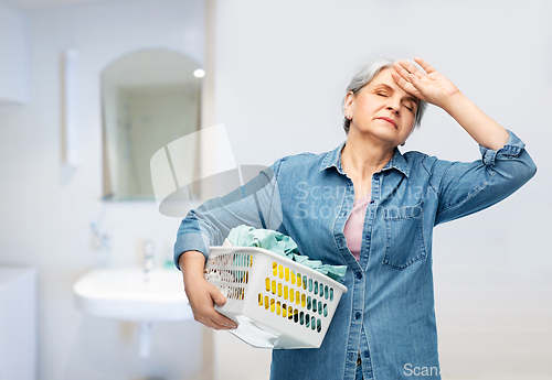 Image of tired senior woman with laundry basket