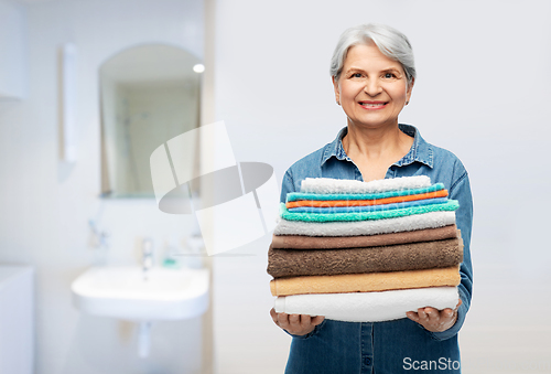 Image of smiling senior woman with clean bath towels