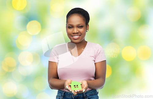 Image of smiling african american woman holding green house