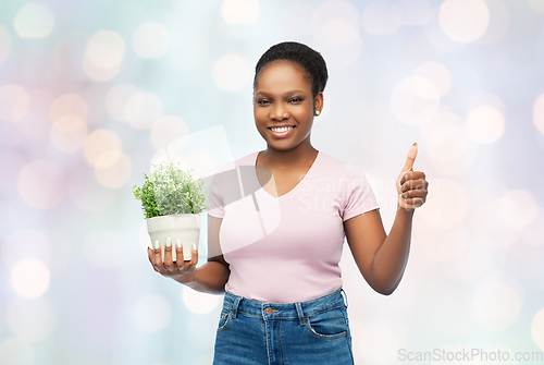 Image of happy african woman with flower showing thumbs up