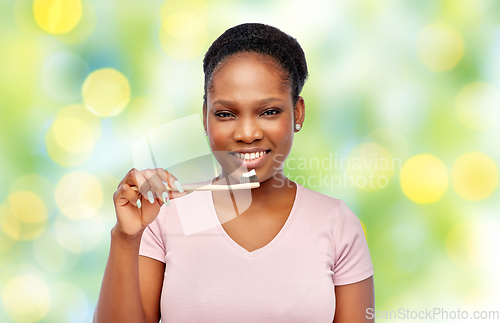 Image of smiling woman with toothpaste on wooden toothbrush