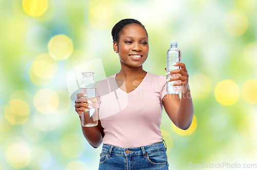 Image of happy woman with plastic and glass bottle of water