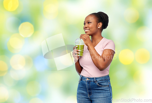 Image of happy african american woman drinking green juice