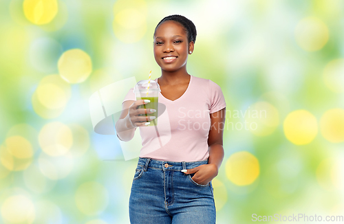 Image of happy african american woman drinking green juice